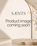 A beige and cream mockup image with the text 'SÆNTS Product image coming soon' displayed in the center, featuring a minimalist archway, soft shadows, and a round stone pedestal at the bottom.